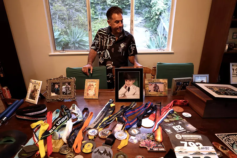 A person standing behind a table with multiple picture frames and medals