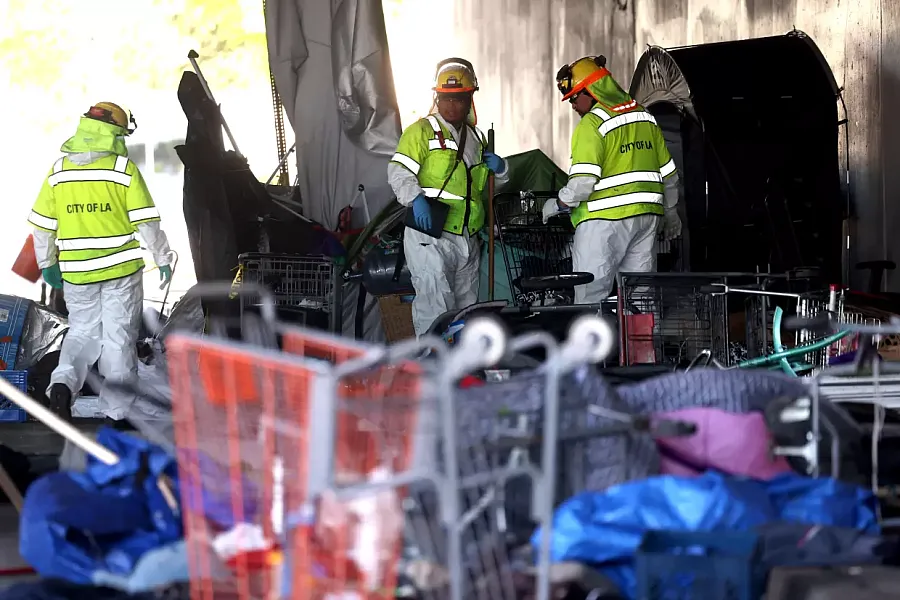 Sanitation crews remove belongings from a homeless encampment