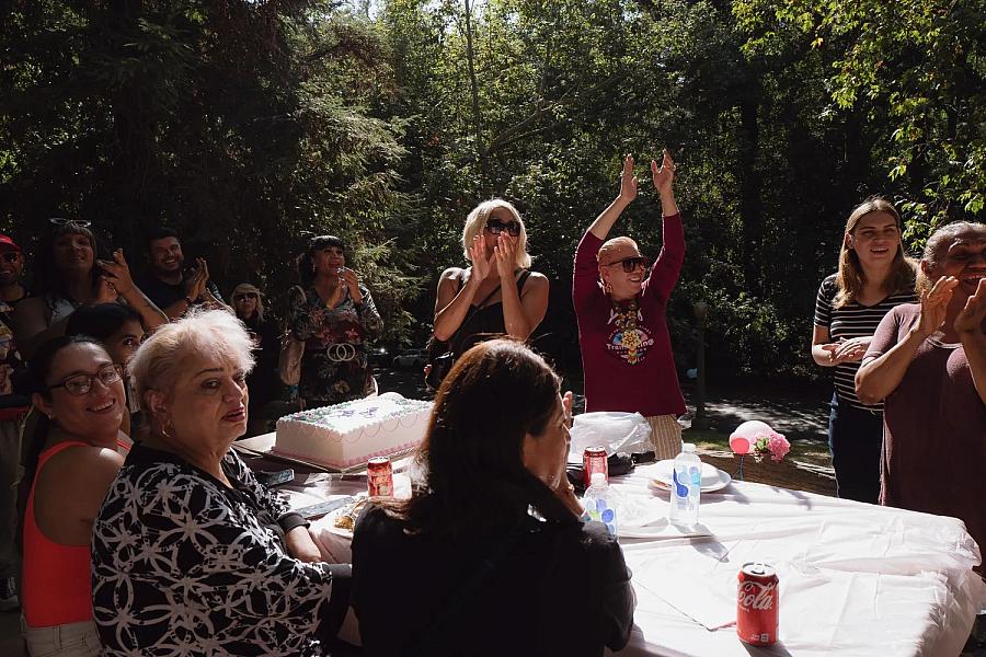 Image of people across table in outdoors celebrating and clapping