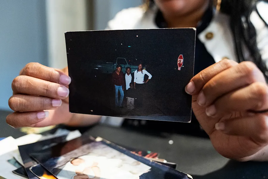 Person showing photograph of four persons against a truck in dark