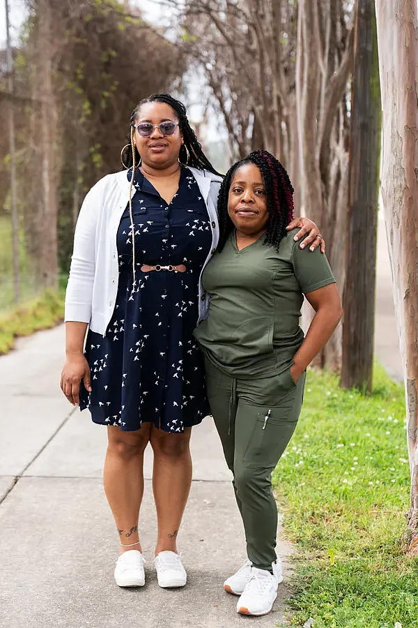 Two people standing on a concrete road against trees