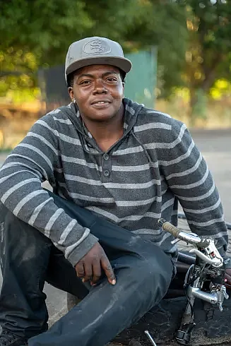 Person in gray shirt with cap, side pose