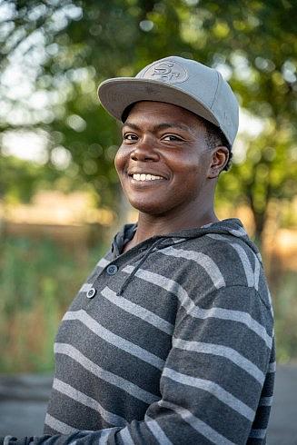 Person in gray shirt with cap, side pose