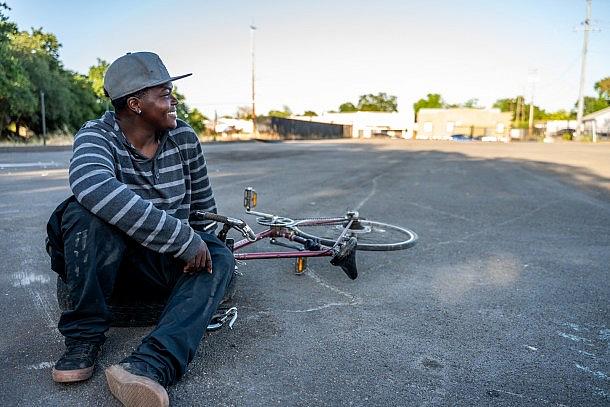 Person in gray shirt with cap, sitting pose