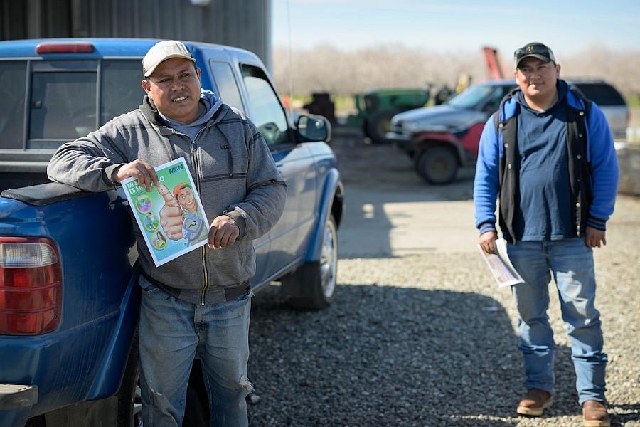 Image of two people besides a car, one person is holding a drawing