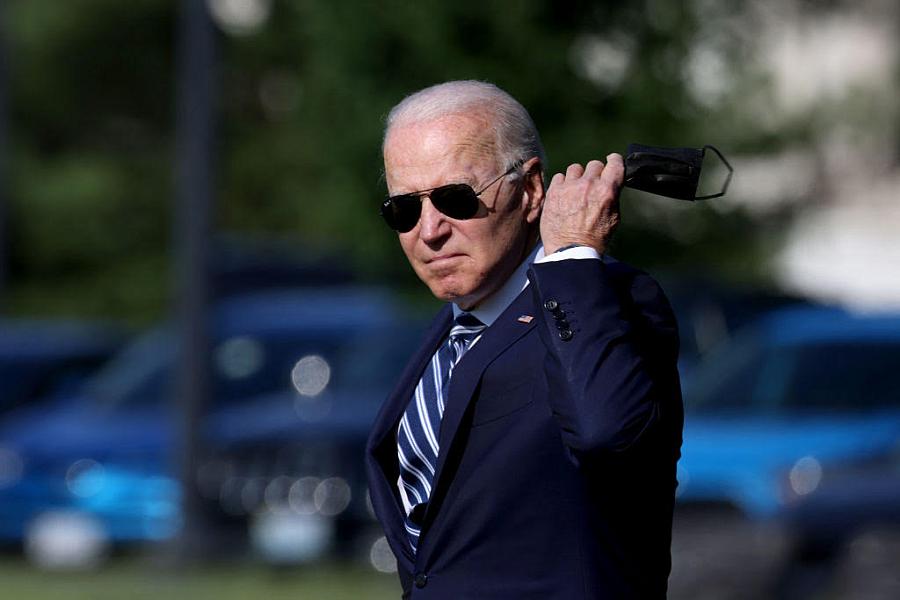 President Joe Biden looking in a camera with mask in his hand