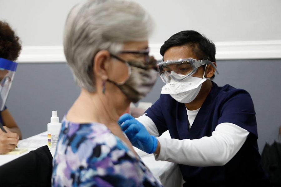 Healthcare worker vaccinating a lady.