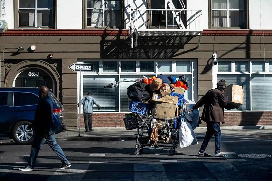 Image of a man moving its belongings on the trolley through Skid Row