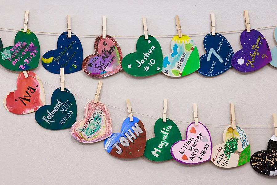 Small heart pieces hanging on the wall with baby names on it.