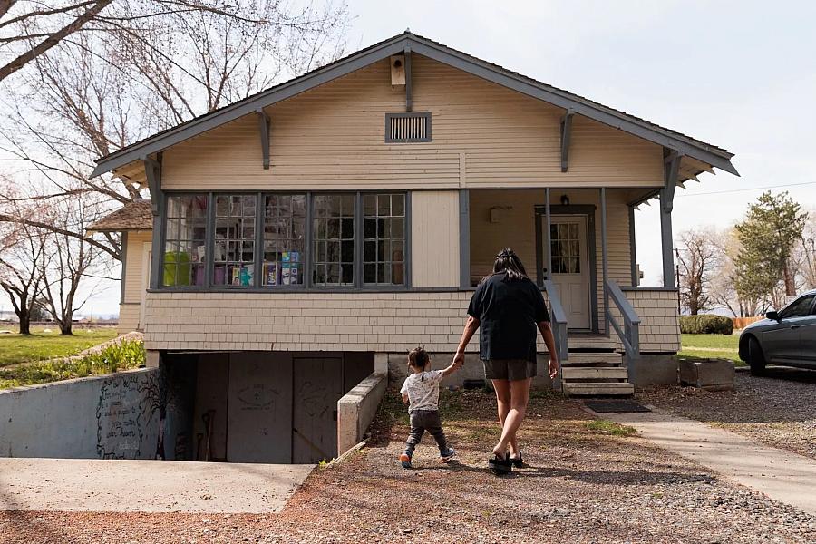 A person holding child's hand walking to home