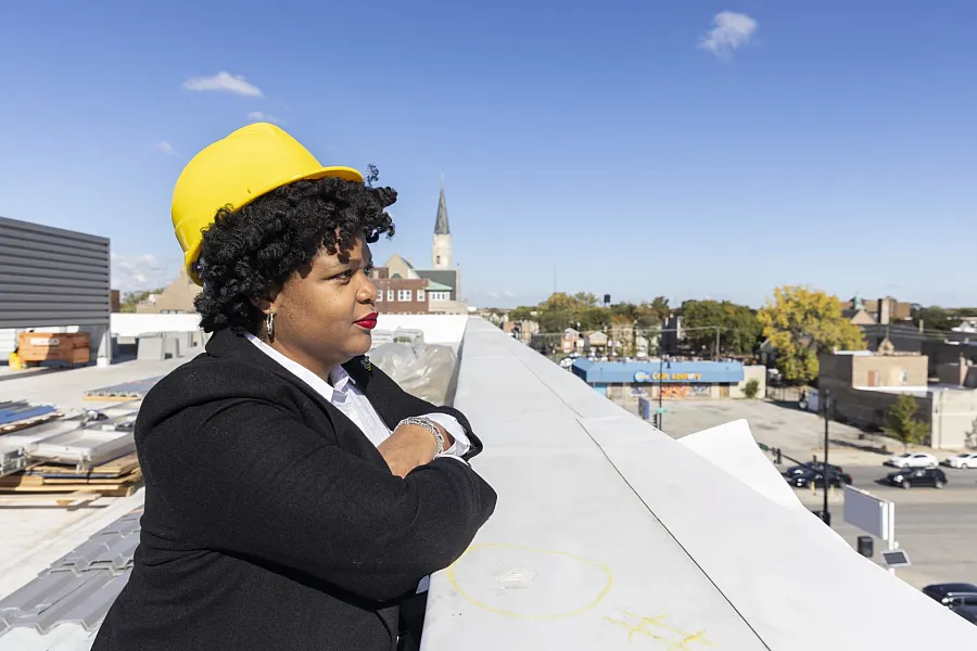 A person with a helmet at a construction site looking from top of a building 