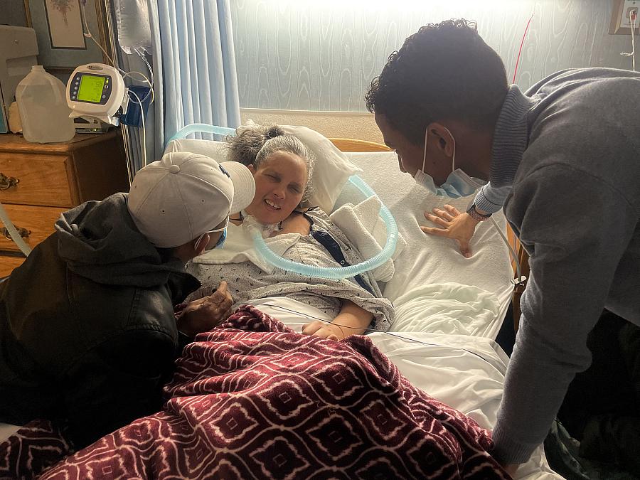 A person on a bed with others by their side