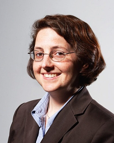 A person with glasses and brown coat 