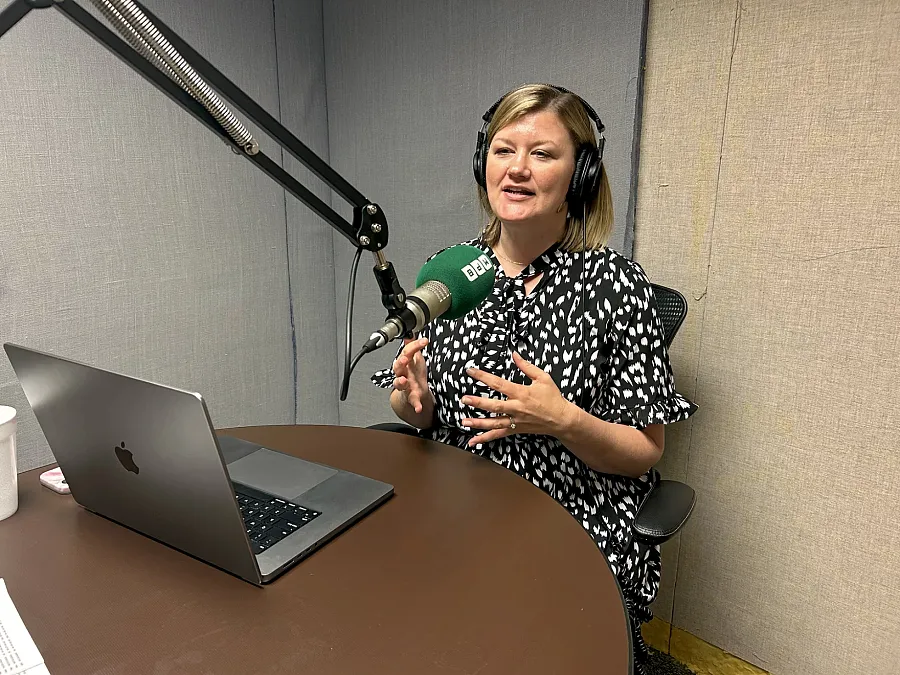 A women with a microphone sitting by a desk