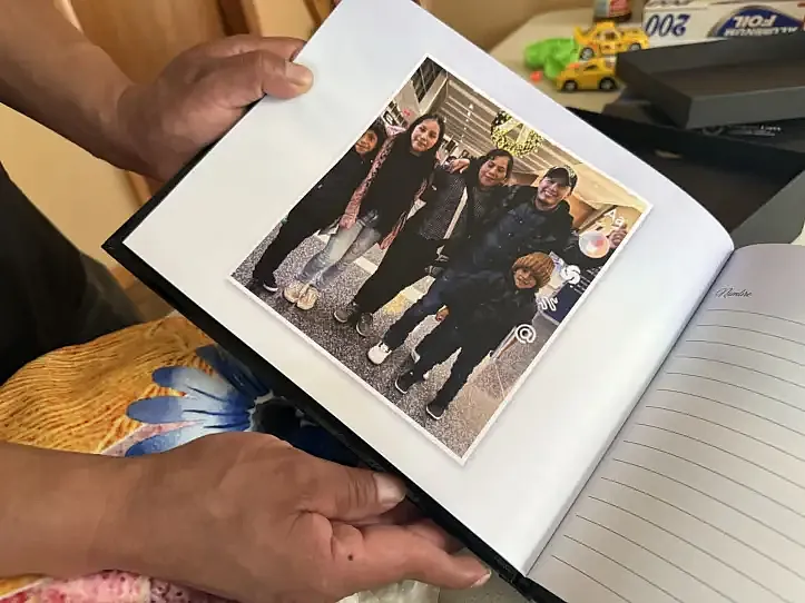 Catarino Cos Castro holds a funeral guest book showing a photo of his wife, Jerónima Quinilla Castro de Cos, and their three children