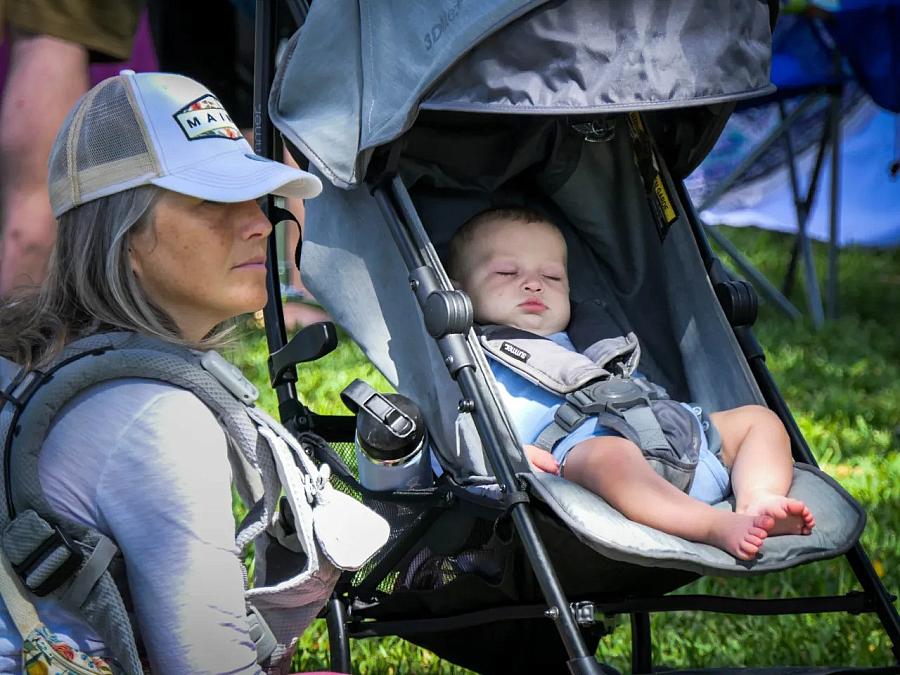 baby in a stroller and person sitting close by