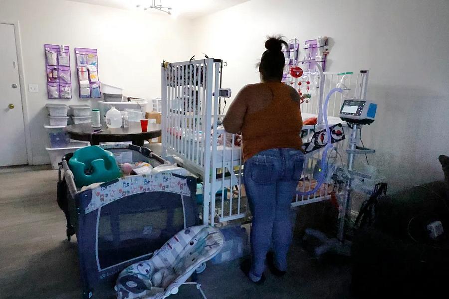 Person standing in front of a crib with medical equipment