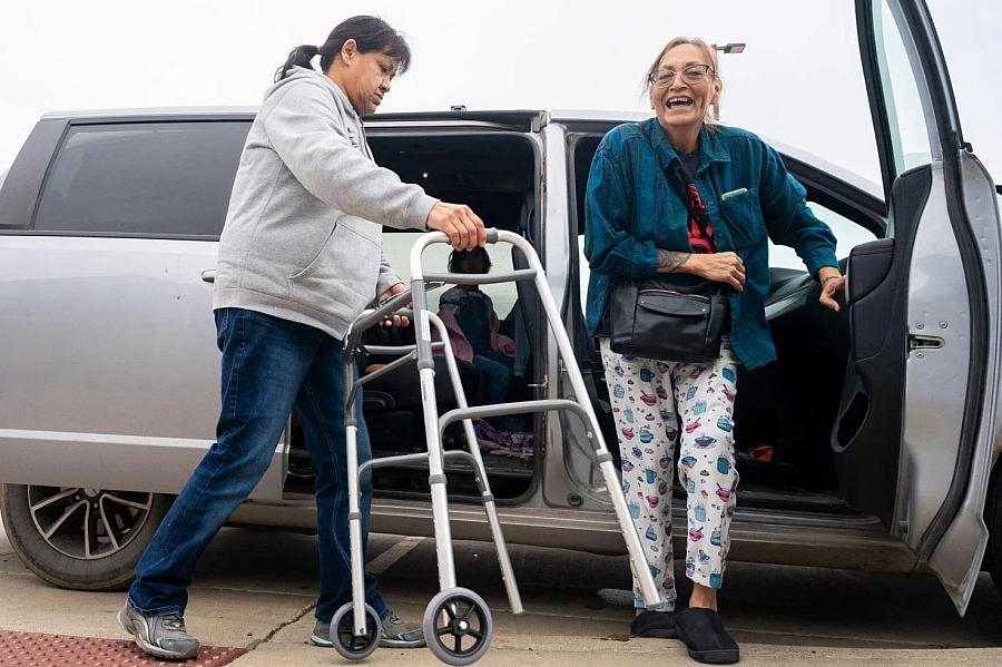 2 people, one holding a walker