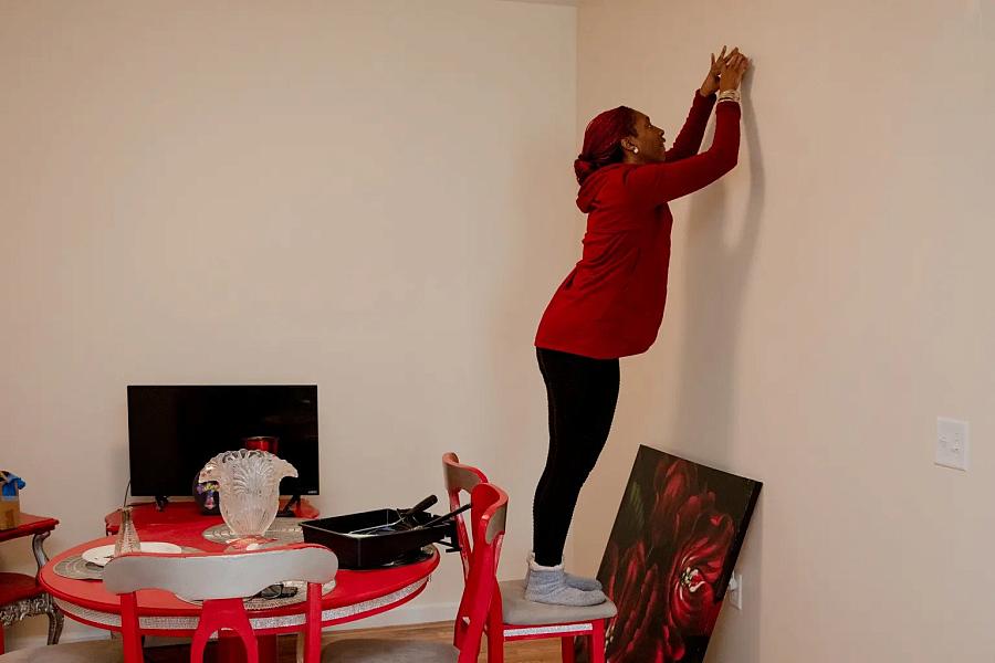A woman trying to insert nail into wall