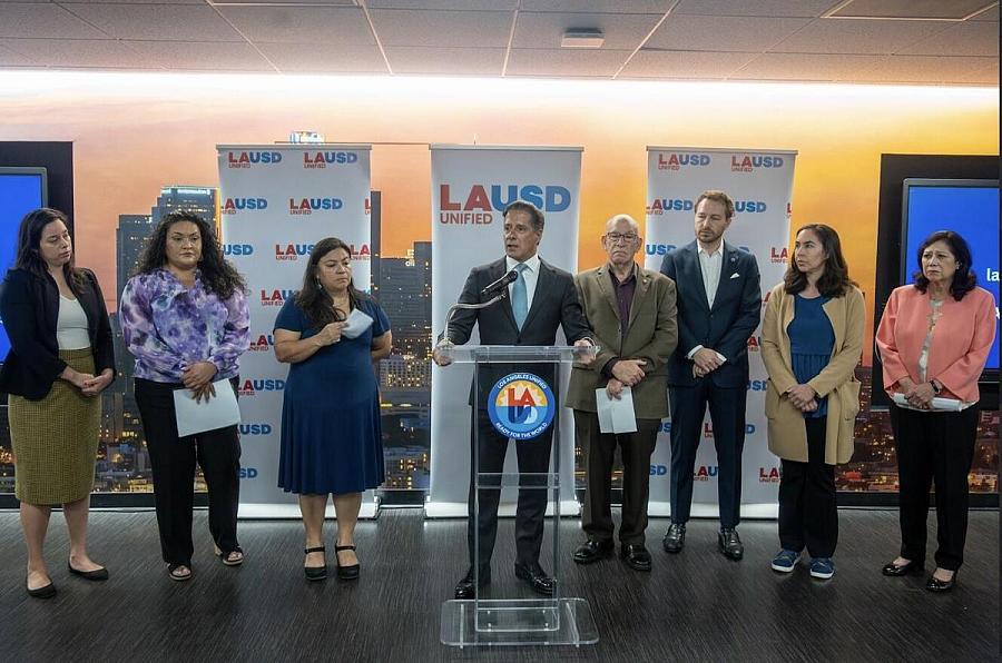 Person standing at a podium, with a group of people next to them