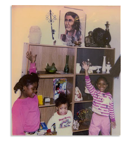 Group photo of three kids against a wooden cupboard having items on the same