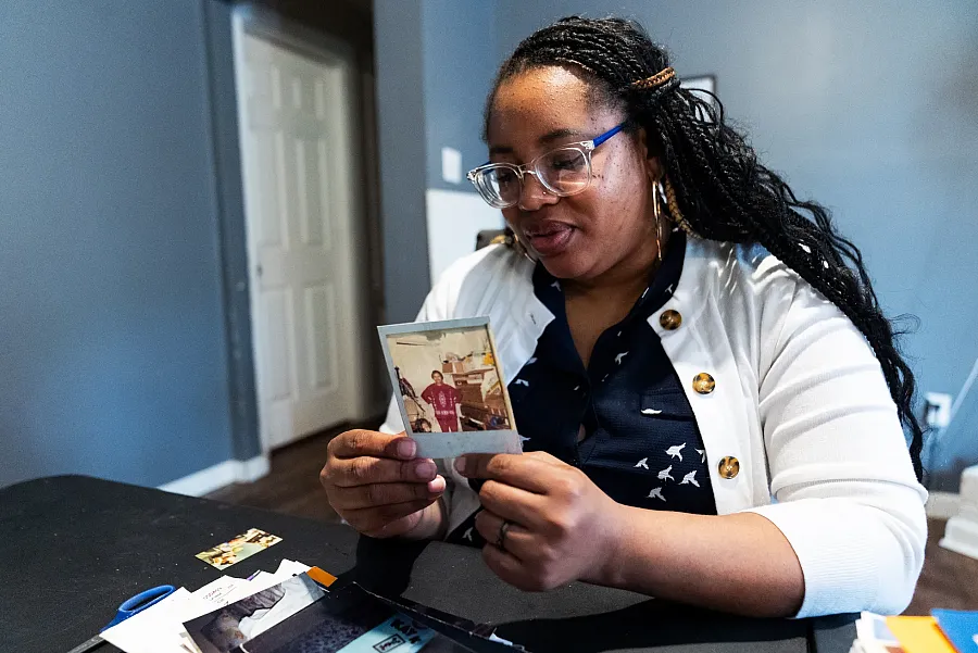 Woman looks at an old photo while seated at a table with papers