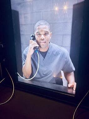 Image of a person talking on a phone from the jail