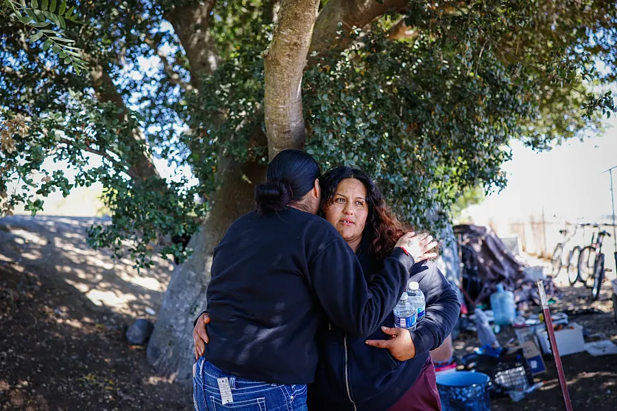 Person hugging other against a tree
