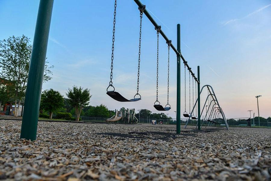 Multiple swings installed in an open playground against a bright blue sky