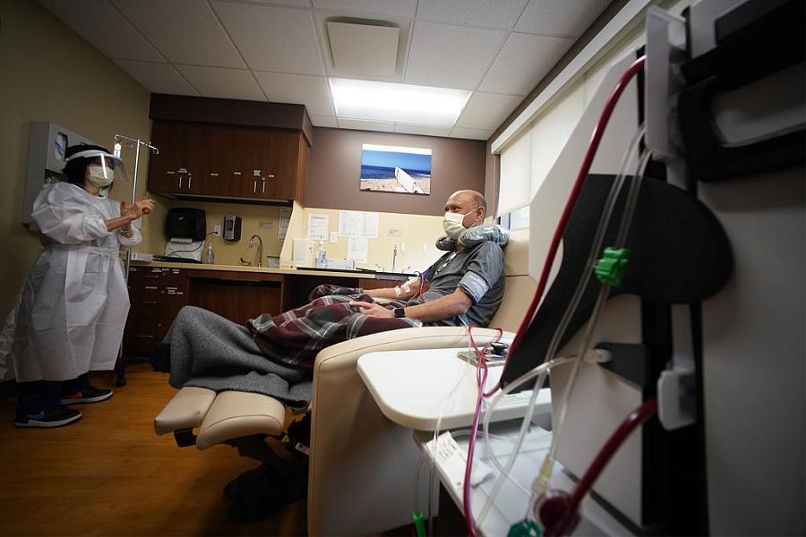 A patient and a health care worker in a dialysis room, patient sitting for examination.