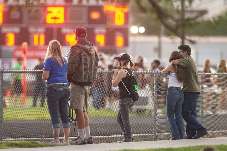 People watch a football game over a fence