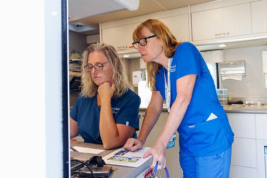 Image of two healthcare workers looking at laptop screen