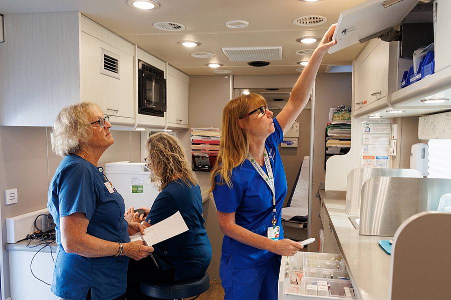 Image of three healthcare workers setting up the mobile clinic.