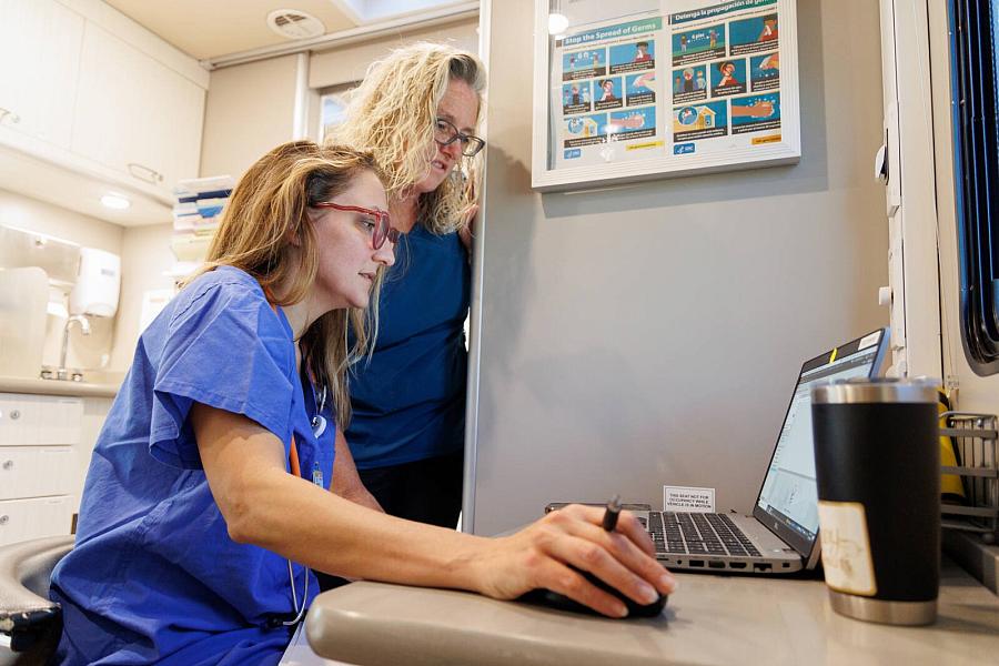 Image of two healthcare workers looking at laptop screen