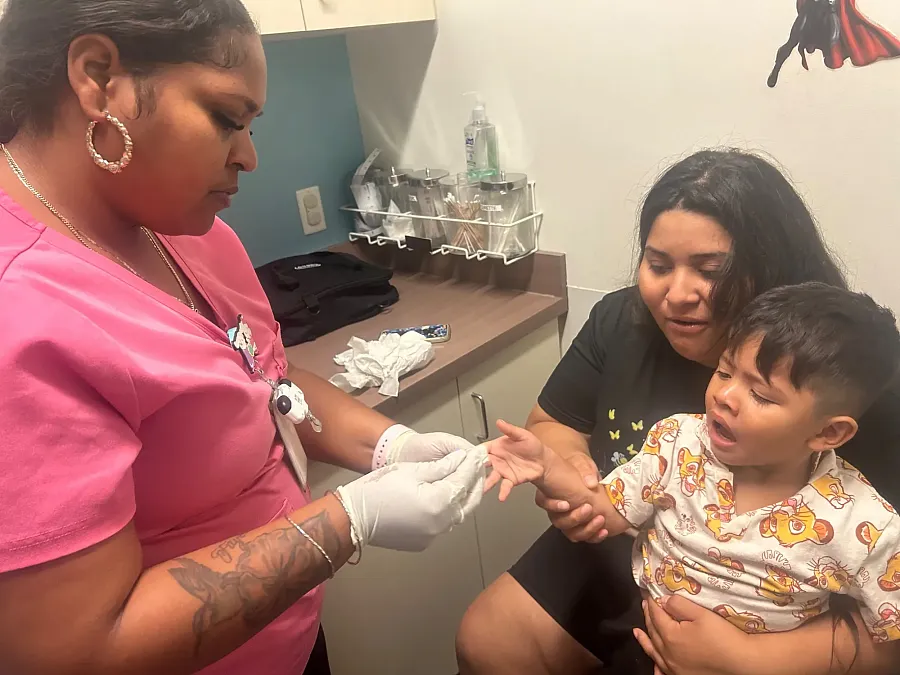 Three-year-old Liam Guzman Romero, held by his mother Gretty Romero, gets his blood lead levels teste