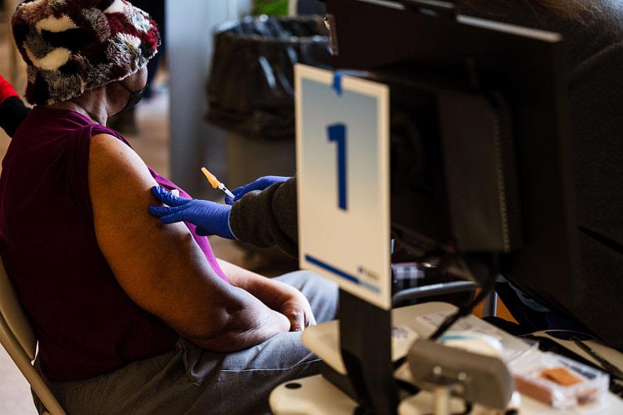 Image of a person sitting on chair being vaccinated