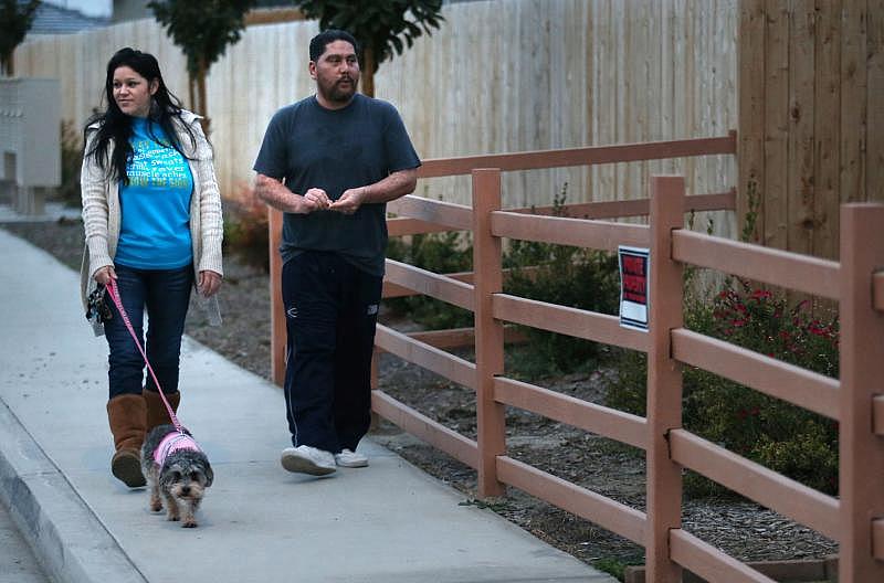 Juan and Julie Solis take their dog Gigi on a walk around their neighborhood.