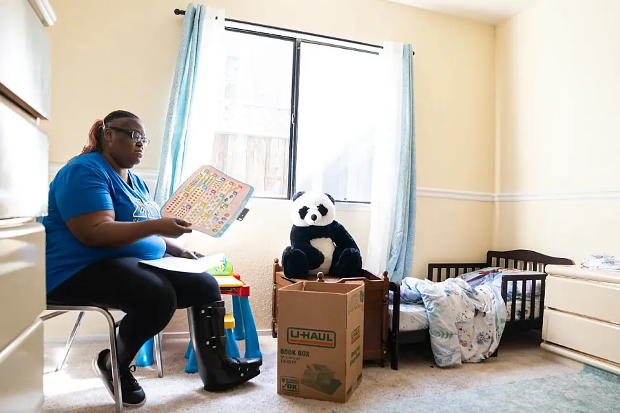Person in blue top sitting on a chair in a room