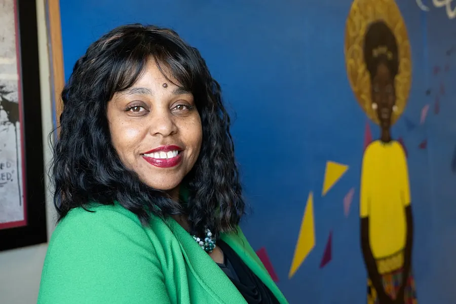 Person in green coat in a room with blue wall