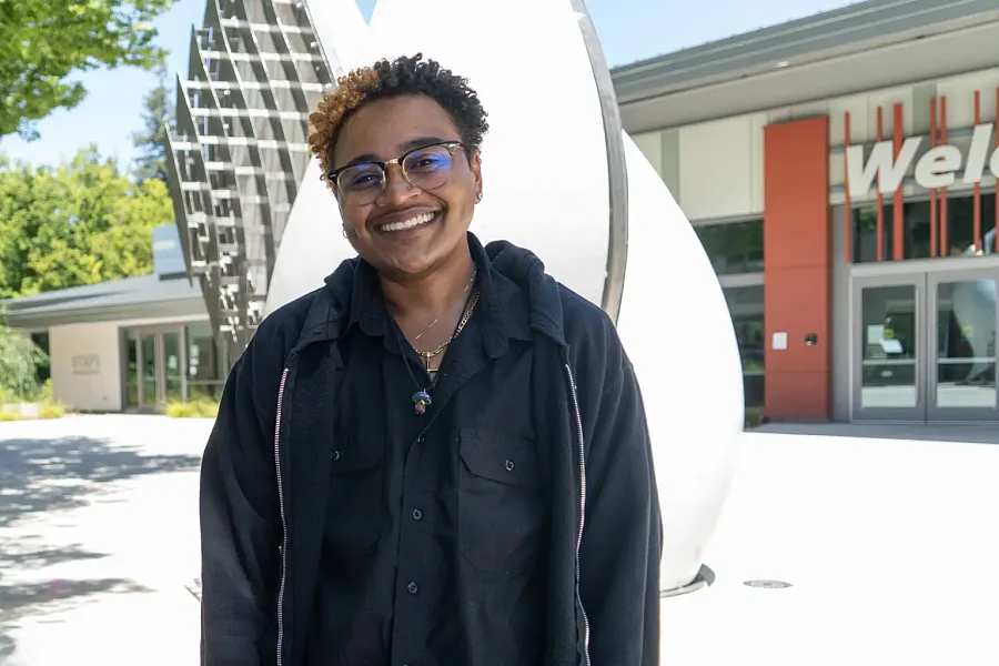 Person standing outdoors wearing black top and spectacles