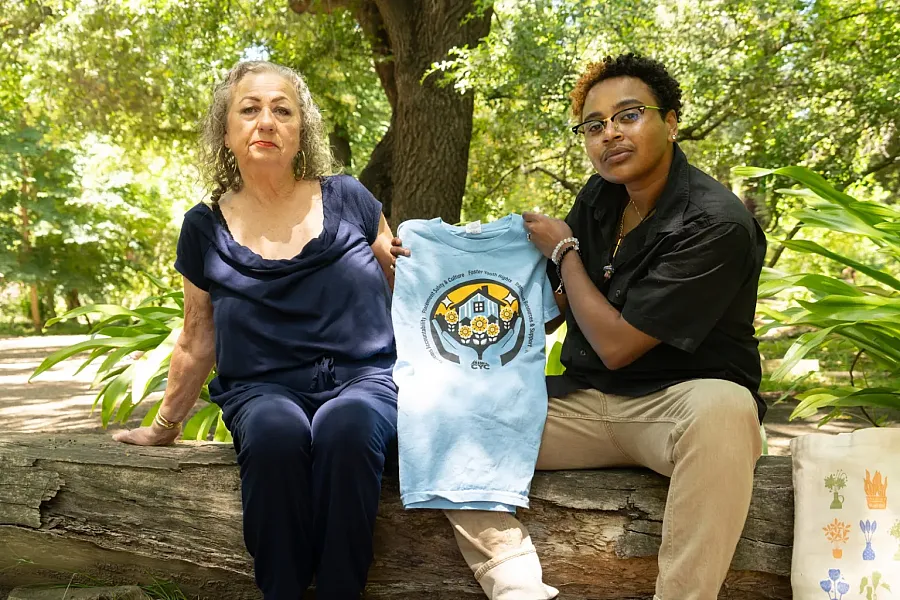 Two people sitting outdoor and person to right showing a blue piece of cloth