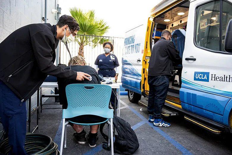 Healthcare workers examining an addicted person sitting on a chair.