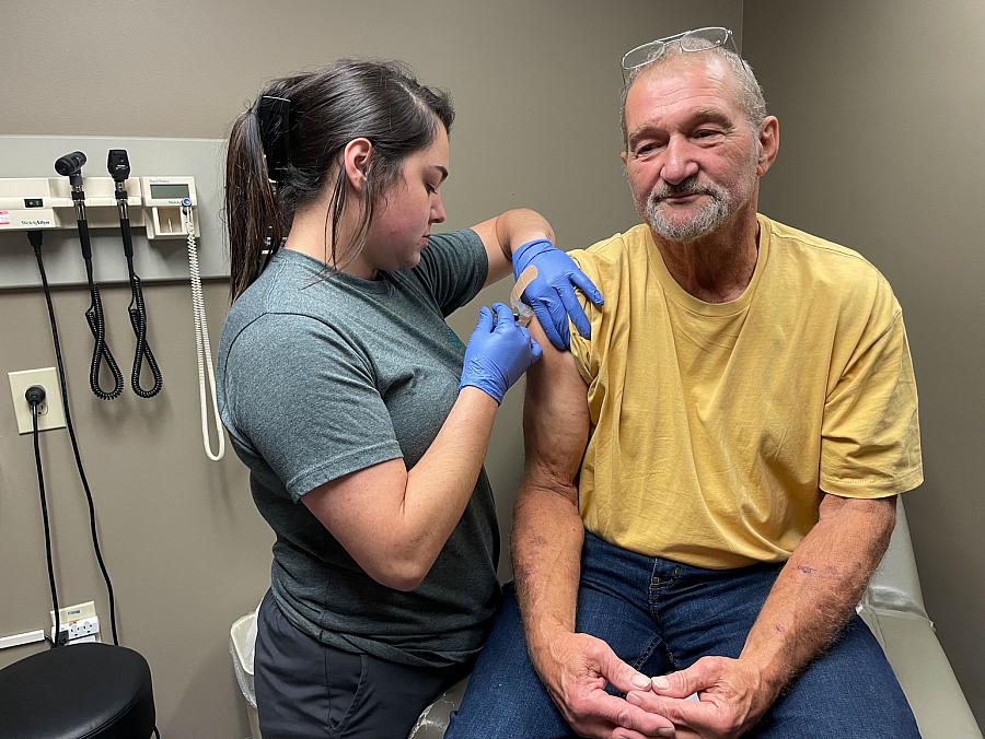 Person giving someone an injection in the arm