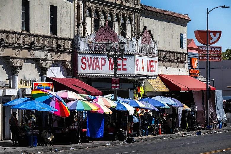 Image of umbrella covered pavement where vendors are selling items