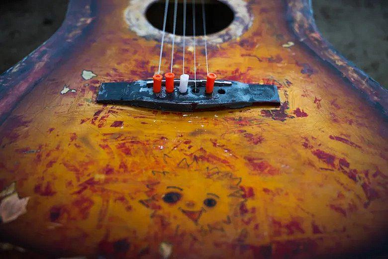 An image of a broken guitar fixed with syringe caps