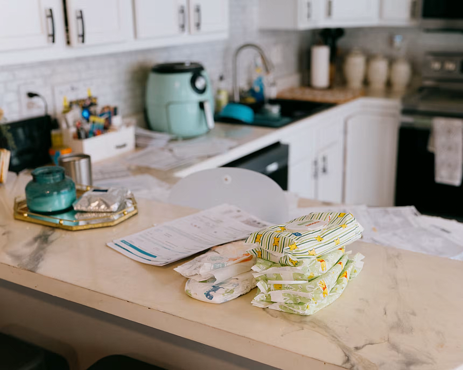 a marble kitchen counter with bills, diapers and wipes on it