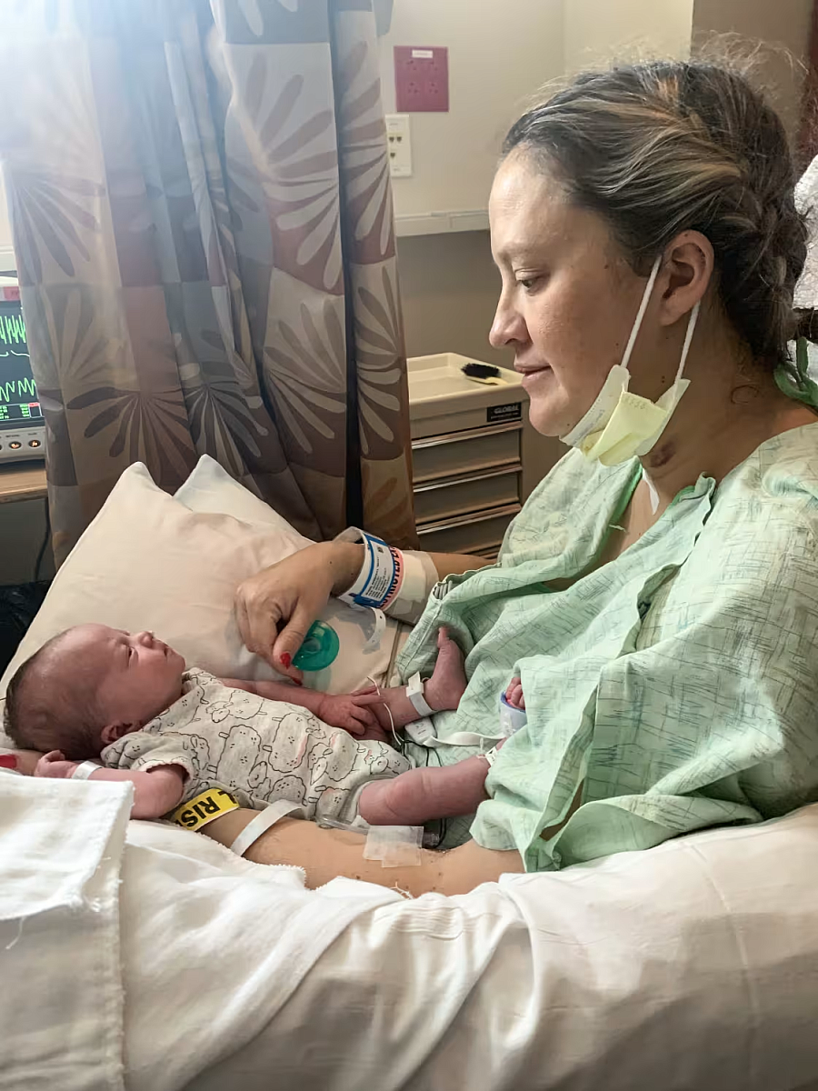 Person in a hospital gown with a baby in their lap