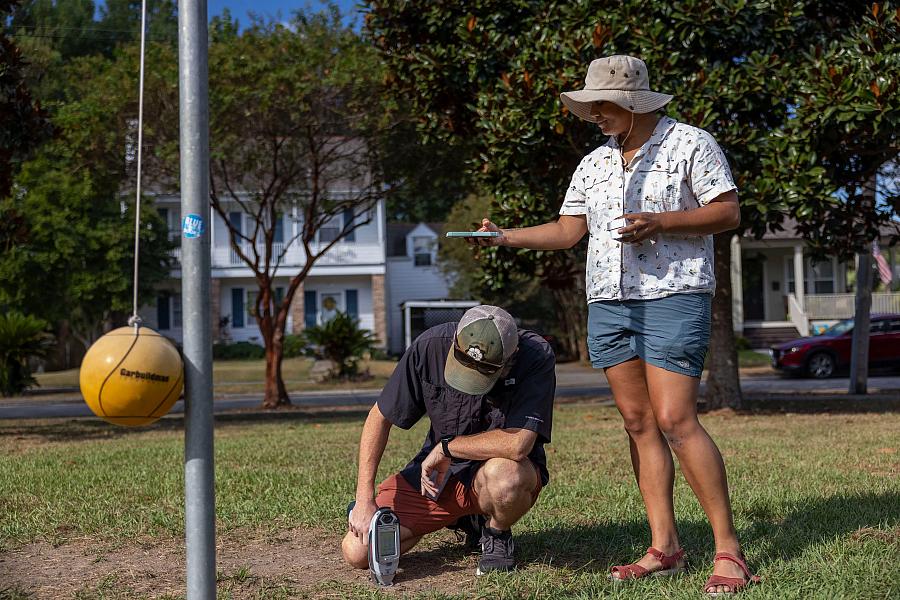 Two people testing lead levels on a ground