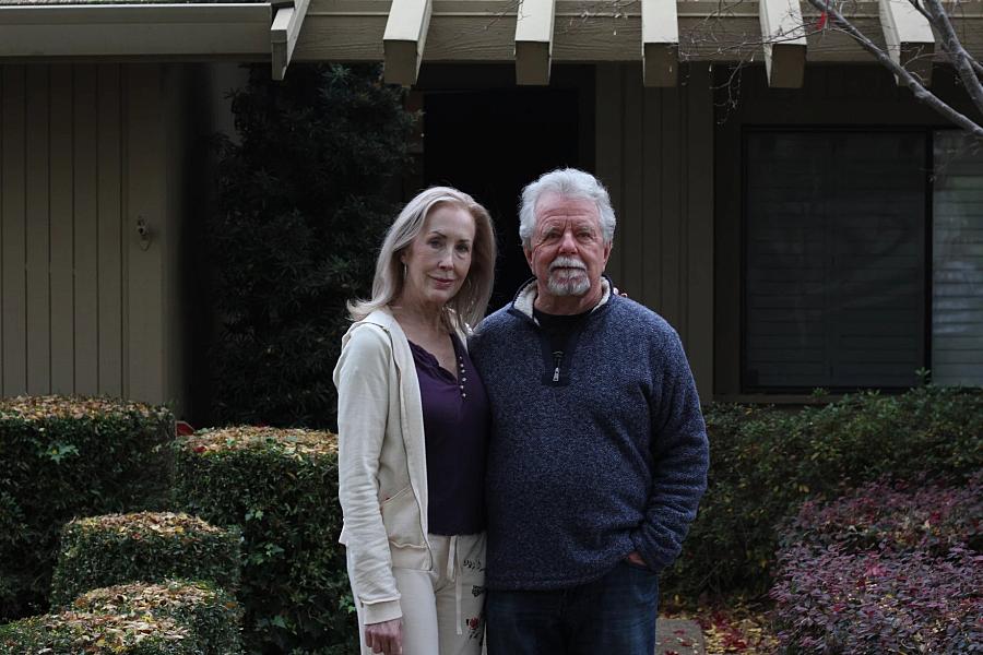 Image of two people standing in front of their home.