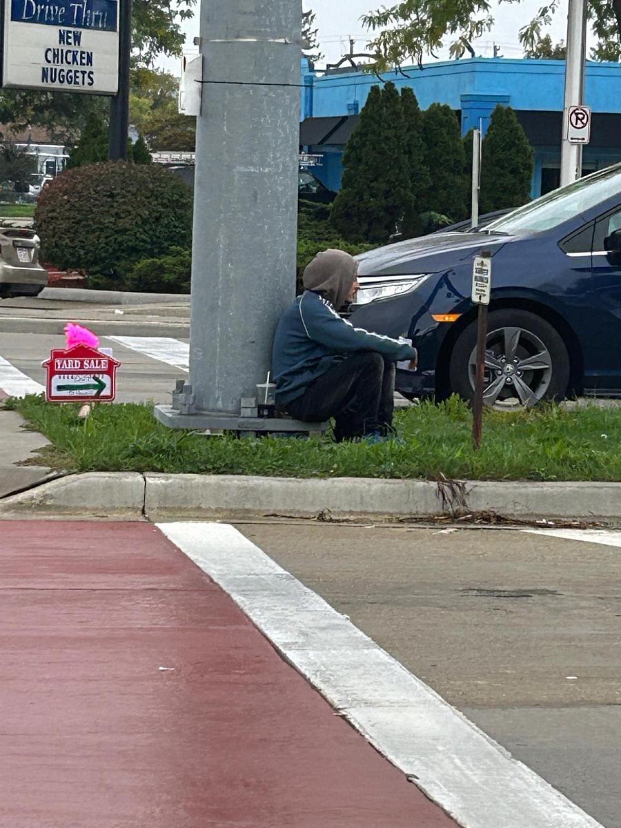 A person sitting on sidewalk.